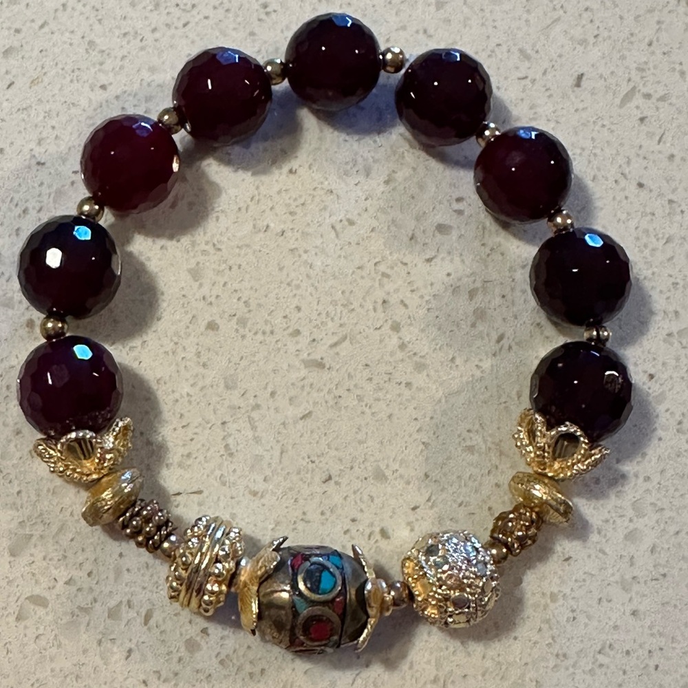 Maroon colored beaded stretch bracelet with gold tone accents. Preowned